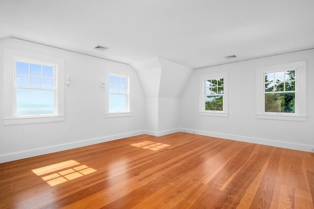 additional living space featuring lofted ceiling, light wood finished floors, baseboards, and visible vents