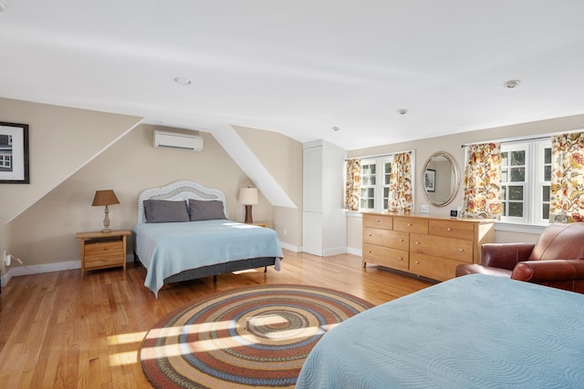 bedroom featuring lofted ceiling, a wall mounted air conditioner, and light wood-type flooring