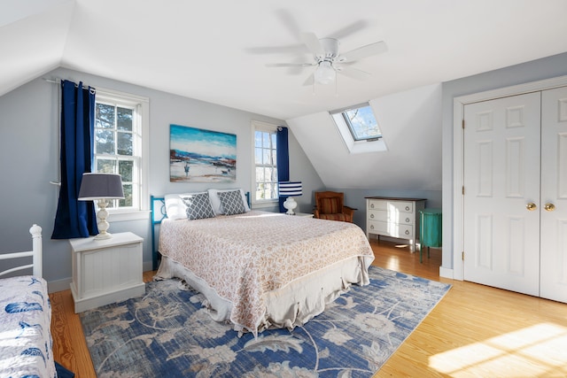 bedroom featuring ceiling fan, wood-type flooring, vaulted ceiling with skylight, and a closet