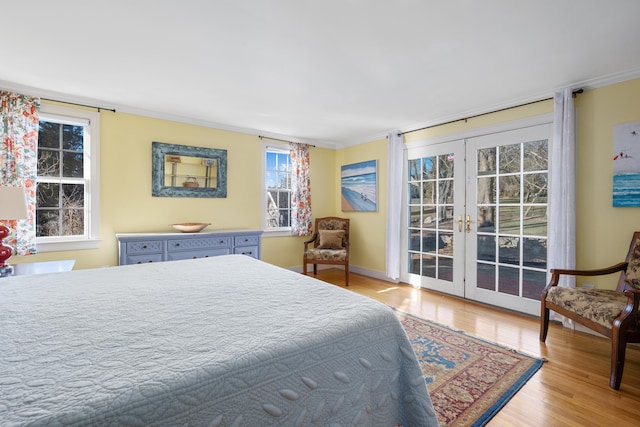 bedroom with crown molding, access to outside, light wood-type flooring, and french doors