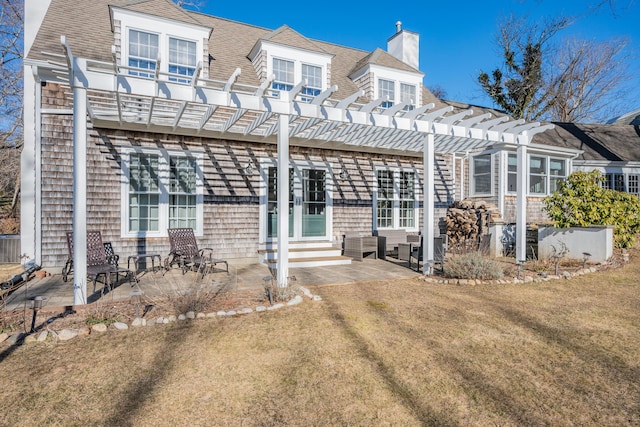 back of property with a pergola, a patio area, and a lawn