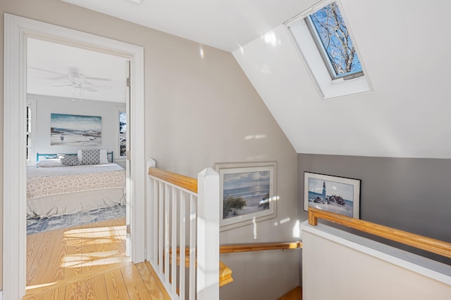 corridor featuring hardwood / wood-style floors and lofted ceiling with skylight