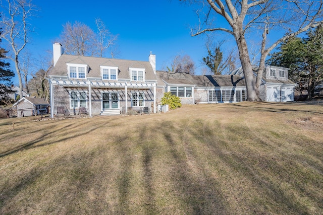 rear view of property with a garage, a pergola, and a lawn