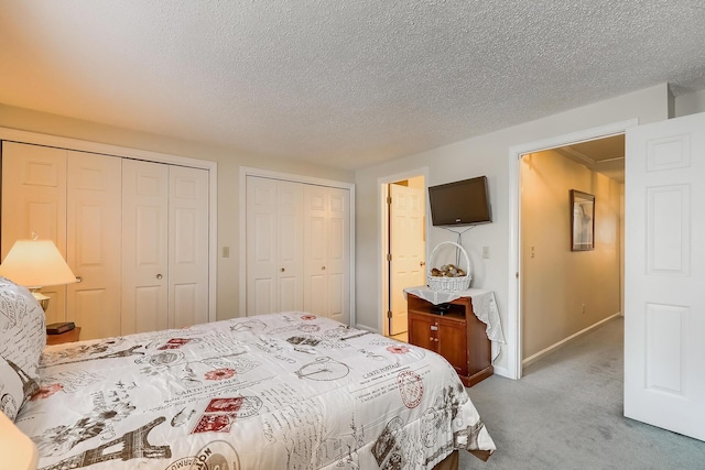 carpeted bedroom featuring multiple closets and a textured ceiling