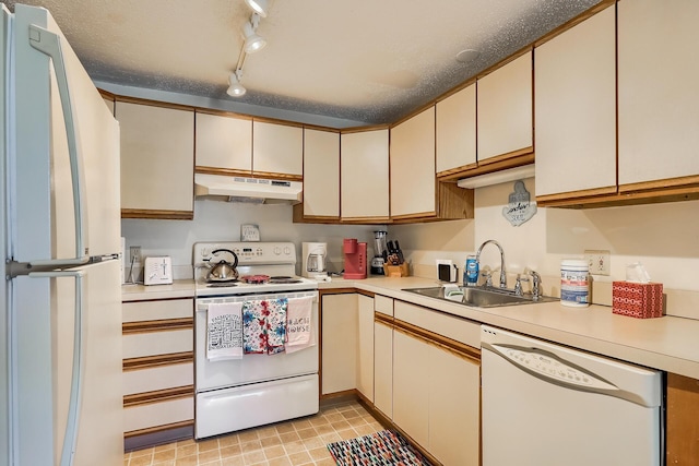 kitchen with sink, white appliances, track lighting, and a textured ceiling