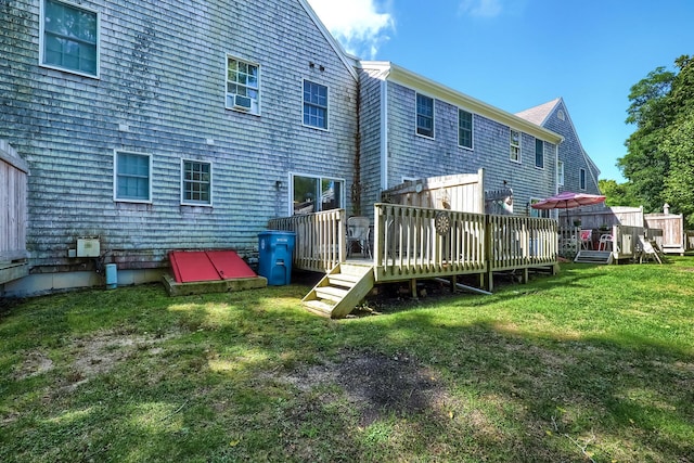 back of property featuring a wooden deck and a lawn