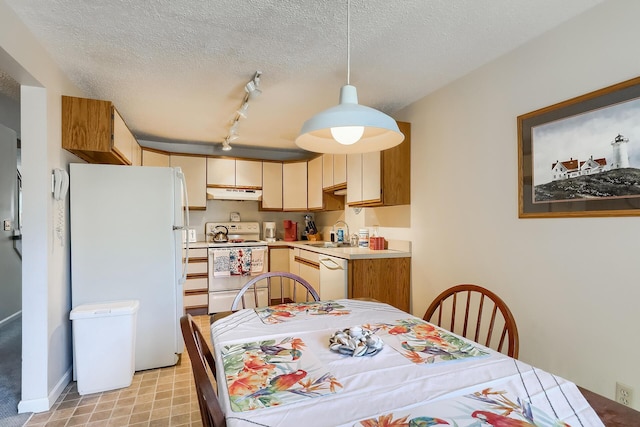 kitchen featuring sink, decorative light fixtures, a textured ceiling, track lighting, and white appliances