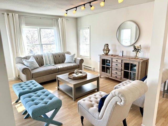 living room with light hardwood / wood-style floors, a textured ceiling, a baseboard heating unit, and track lighting