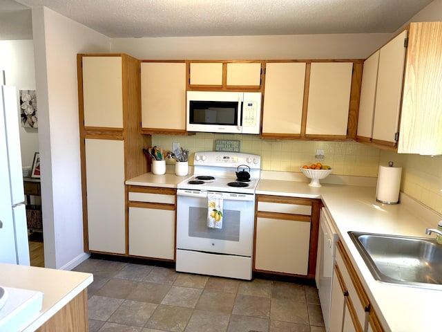 kitchen featuring sink, white appliances, decorative backsplash, and a textured ceiling