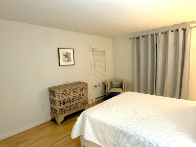 bedroom featuring baseboard heating and wood-type flooring