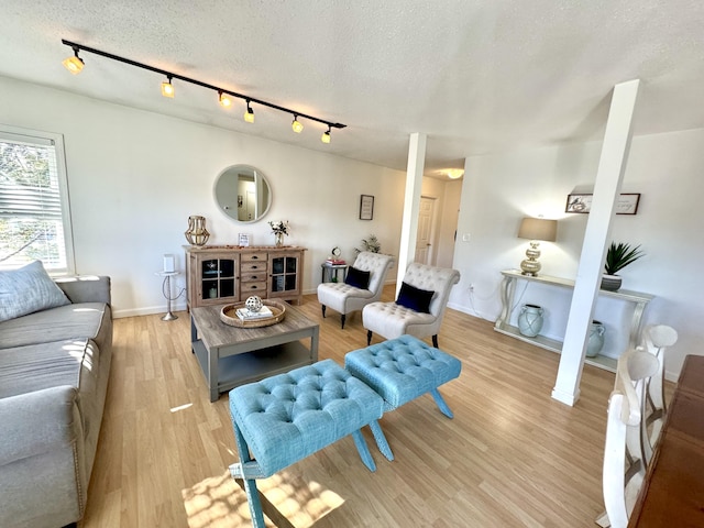 living room featuring track lighting, light hardwood / wood-style flooring, and a textured ceiling