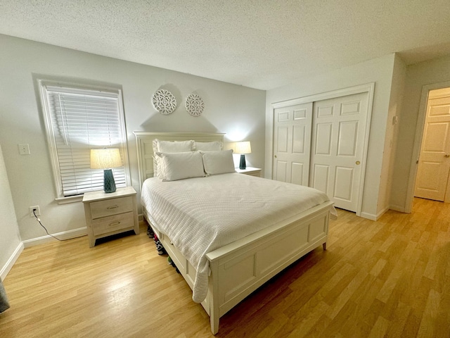 bedroom with light hardwood / wood-style floors, a textured ceiling, and a closet