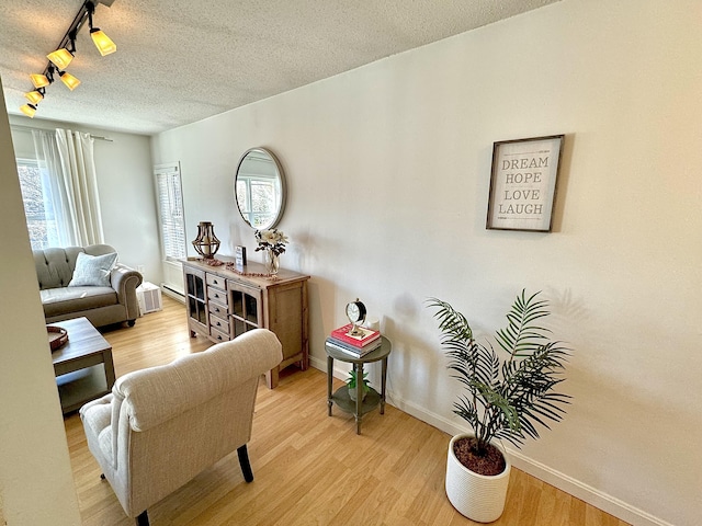 sitting room featuring track lighting, light hardwood / wood-style floors, and a textured ceiling