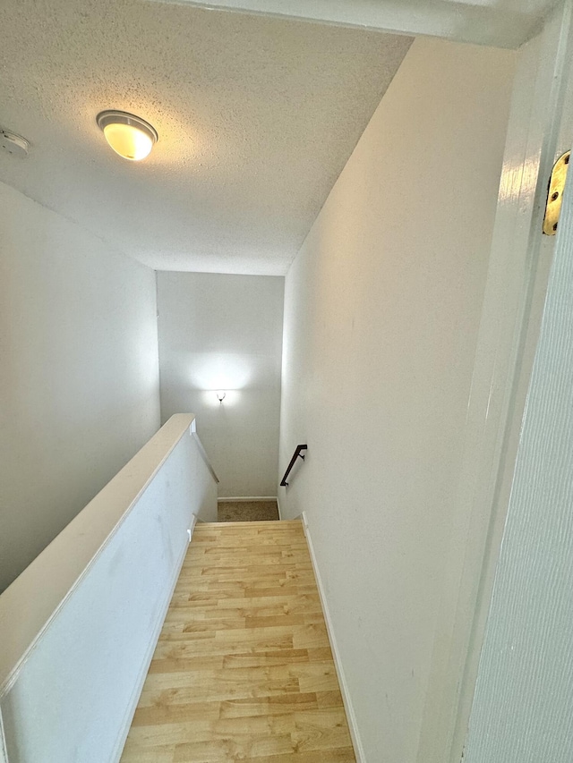 stairs with a textured ceiling and wood-type flooring