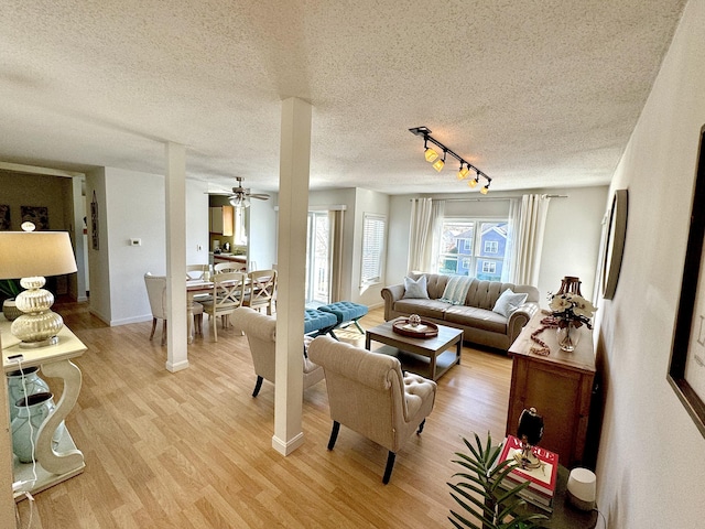 living room with track lighting, ceiling fan, light hardwood / wood-style floors, and a textured ceiling