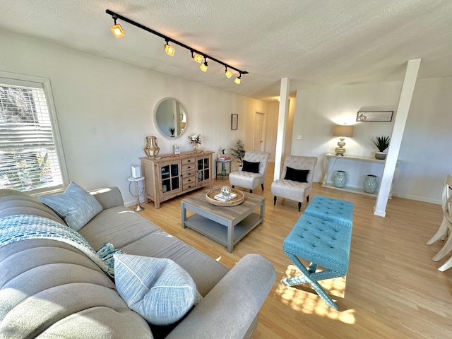 living room with a textured ceiling, light hardwood / wood-style flooring, and track lighting