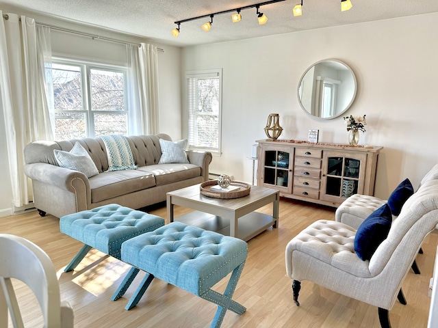 living room featuring rail lighting, a textured ceiling, and light hardwood / wood-style flooring