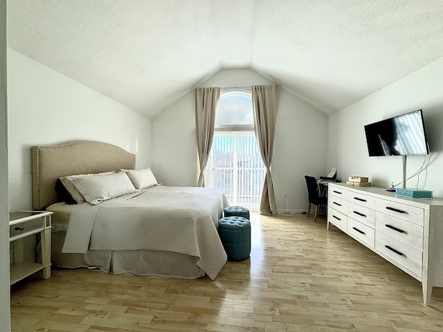 bedroom featuring vaulted ceiling, light hardwood / wood-style floors, and a textured ceiling