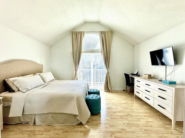 bedroom featuring light hardwood / wood-style floors, a textured ceiling, and lofted ceiling