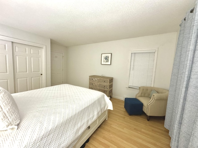 bedroom with a closet, light hardwood / wood-style flooring, and a textured ceiling