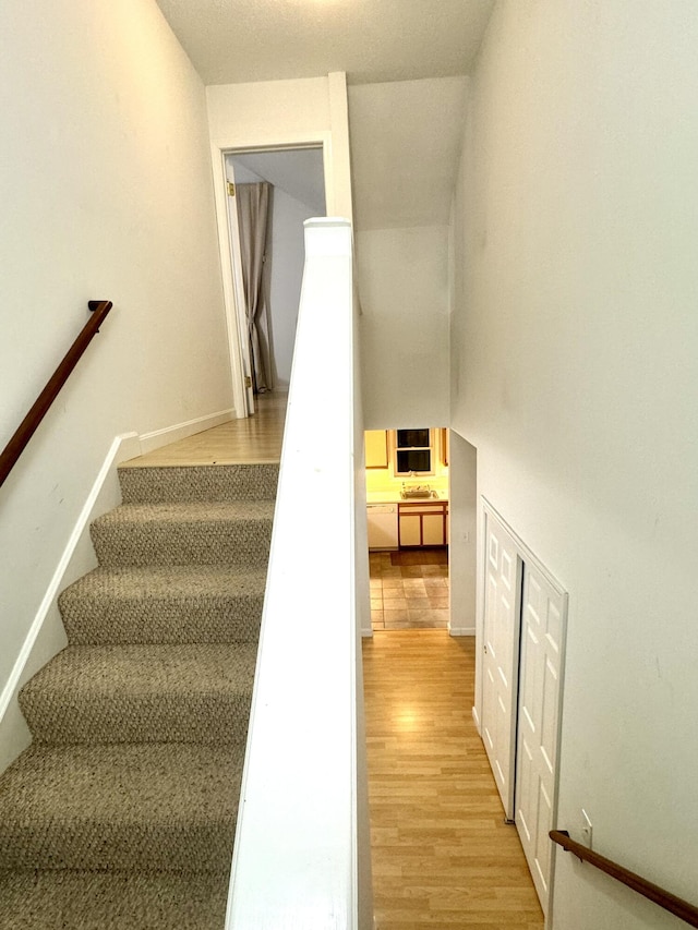 stairs with hardwood / wood-style floors and a towering ceiling