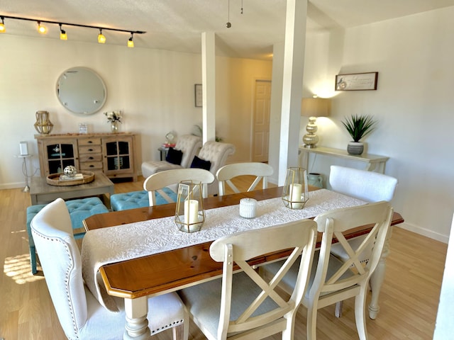 dining space featuring rail lighting and light hardwood / wood-style floors