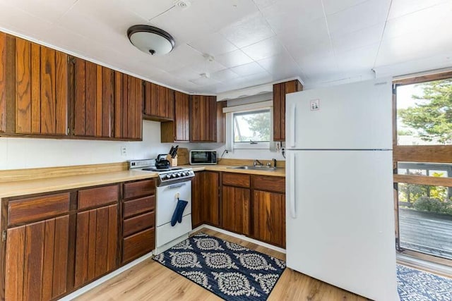 232 Robbins Hill Rd, Brewster, MA 02631 - kitchen featuring a sink, light countertops, light wood-type flooring, and white appliances