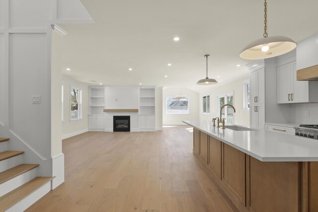 63 Ovington Dr, East Falmouth, MA 02536 - kitchen with light countertops, light wood finished floors, white cabinetry, an island with sink, and a sink