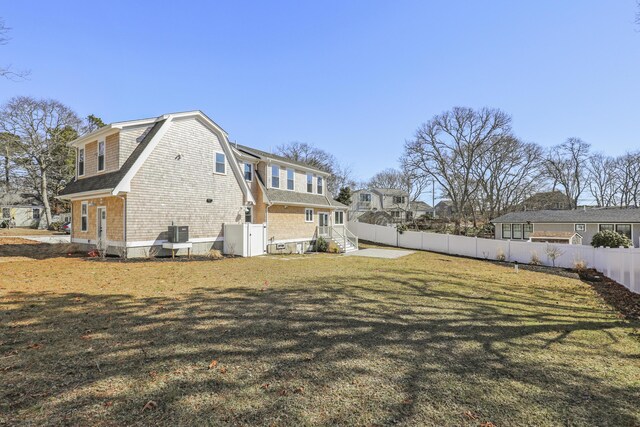 63 Ovington Dr, East Falmouth, MA 02536 - rear view of house featuring central AC unit, a fenced backyard, a gambrel roof, a lawn, and a shingled roof