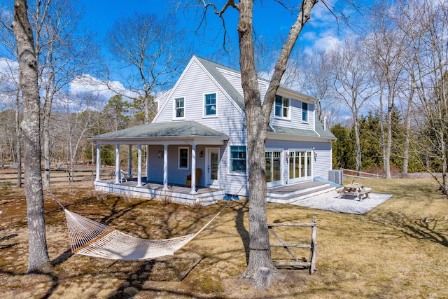 rear view of property featuring a yard, covered porch, an outdoor fire pit, central air condition unit, and a shingled roof