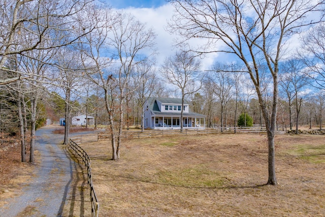 view of front of home with driveway, a porch, and fence