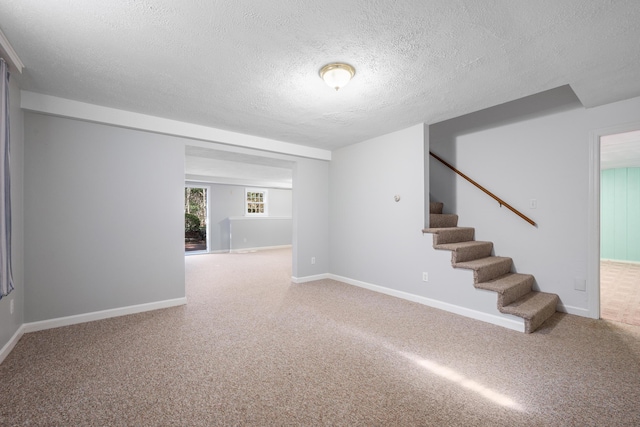 interior space with a textured ceiling, carpet floors, stairway, and baseboards