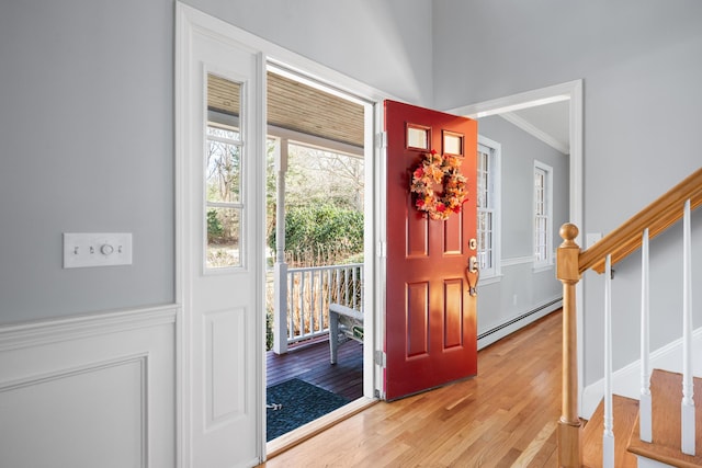 entryway featuring crown molding, stairway, a baseboard radiator, and light wood-style floors