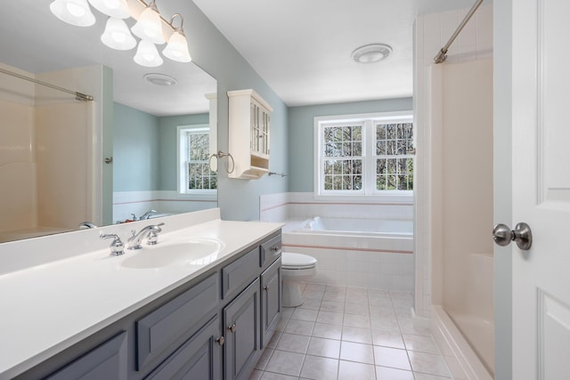 full bathroom featuring a relaxing tiled tub, a shower, toilet, vanity, and tile patterned flooring