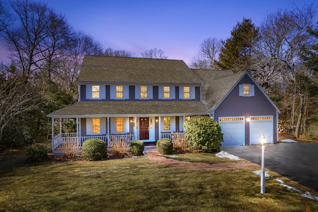 view of front of property with a porch, driveway, a garage, and a lawn