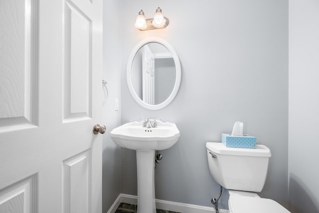 bathroom with a sink, toilet, and baseboards