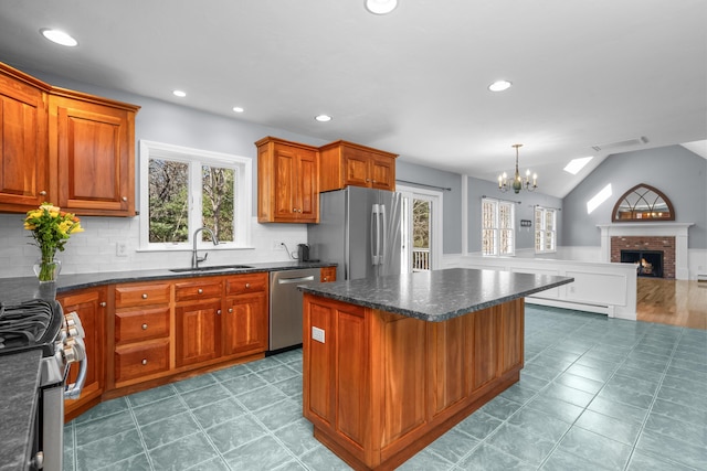 kitchen with a baseboard heating unit, a fireplace, a sink, open floor plan, and appliances with stainless steel finishes