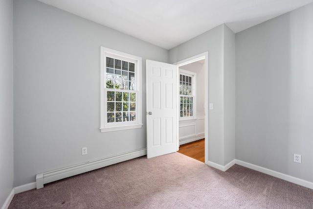 carpeted empty room featuring baseboards and a baseboard heating unit