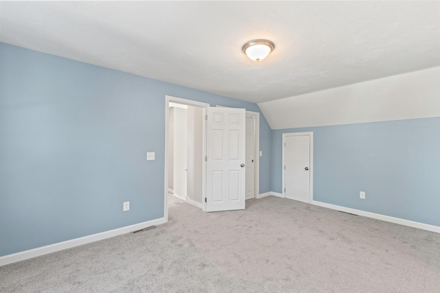 additional living space with light carpet, vaulted ceiling, visible vents, and baseboards