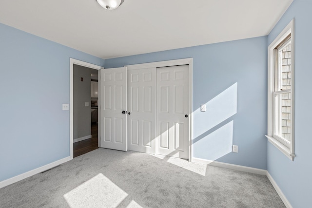 unfurnished bedroom with carpet floors, a closet, and baseboards