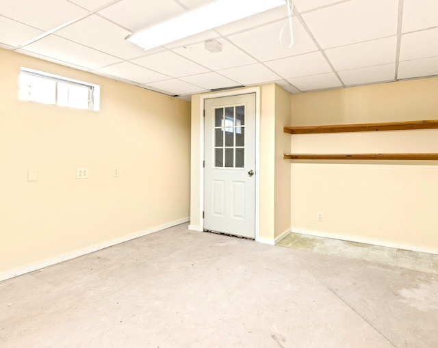 basement featuring a paneled ceiling and baseboards