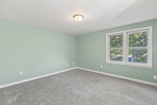 carpeted empty room featuring visible vents and baseboards