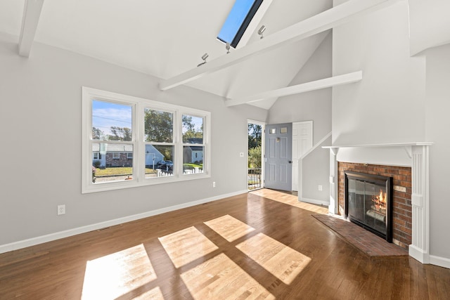 unfurnished living room featuring wood finished floors, visible vents, baseboards, a brick fireplace, and beam ceiling