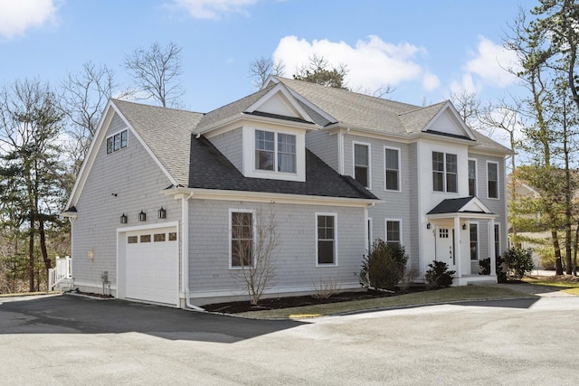 view of front of house with aphalt driveway, an attached garage, and roof with shingles