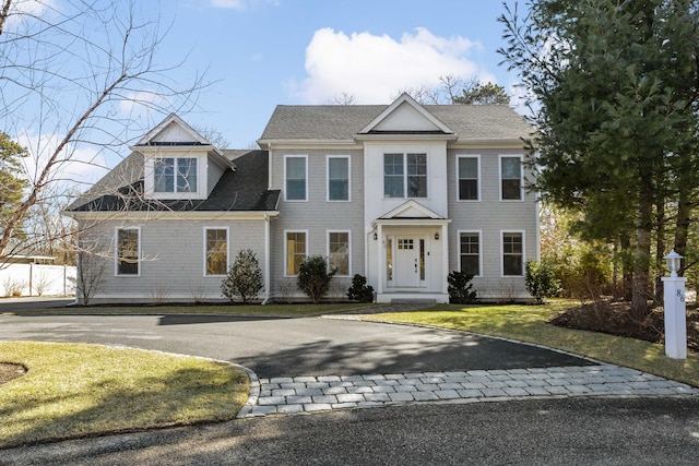 colonial-style house with a front yard, driveway, and a shingled roof