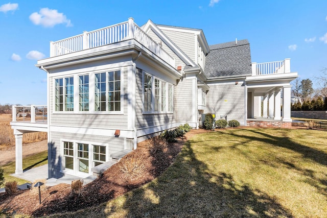 view of side of home featuring a lawn and a balcony