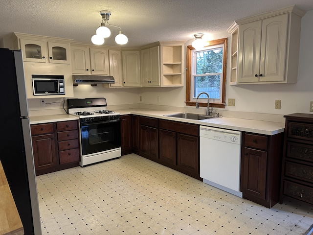 kitchen featuring freestanding refrigerator, white dishwasher, built in microwave, a sink, and gas stove