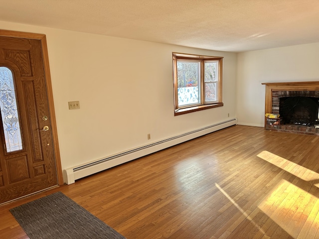 unfurnished living room with a baseboard radiator, a brick fireplace, and hardwood / wood-style flooring