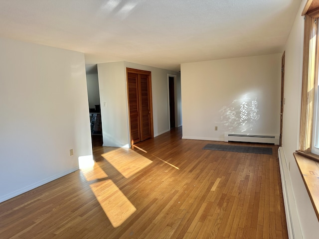 spare room with hardwood / wood-style flooring, a baseboard radiator, baseboards, and baseboard heating