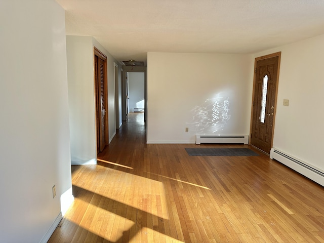 unfurnished room featuring a baseboard heating unit, a baseboard radiator, wood-type flooring, and baseboards